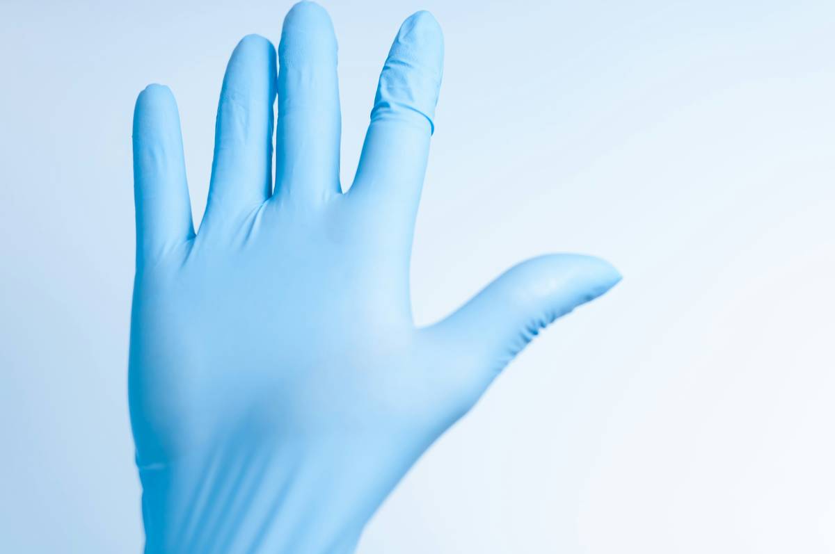 Hand wearing chemical resistant work gloves handling eco-friendly cleaning supplies safely