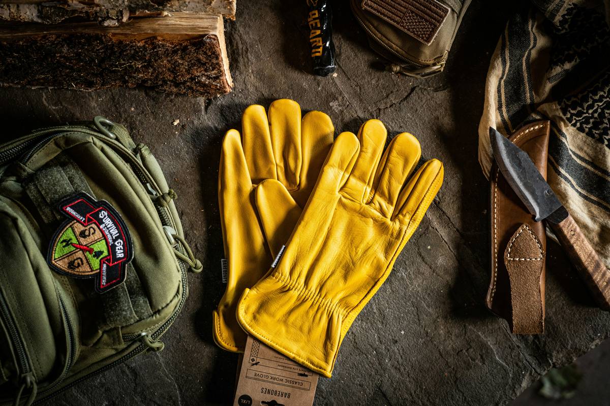 Hand holding compostable gloves australia next to a home compost bin filled with organic waste